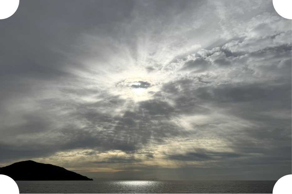 太陽が雲の間から差し込み、海の上に輝く美しい光景。